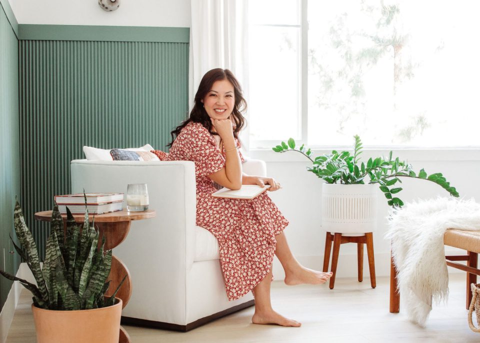 Anita sits in a white chair in her bedroom, journal on her lap