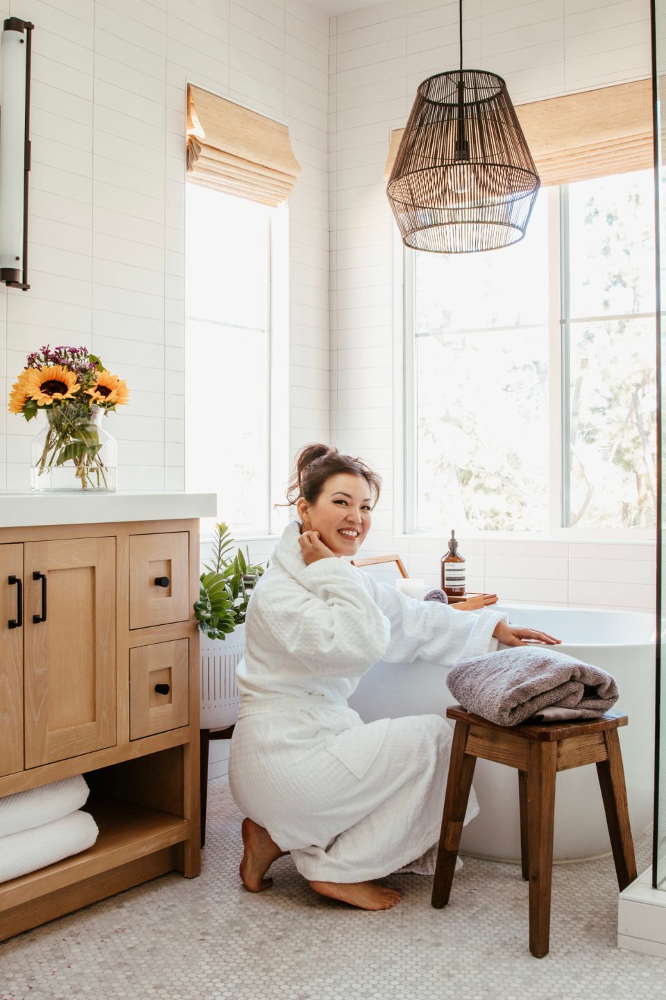 Anita crouches by the bath tub getting ready for a self-care afternoon