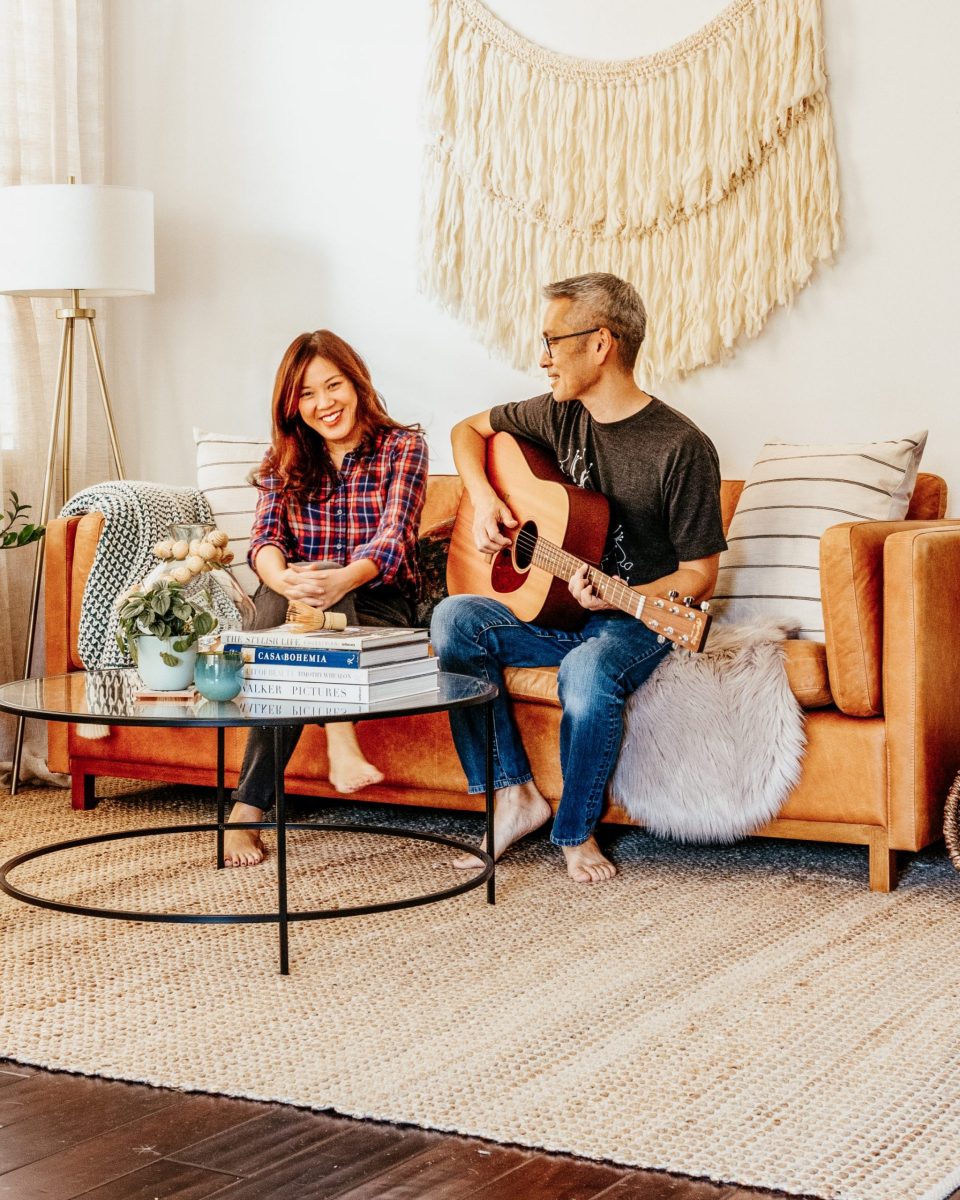 Travis serenades Anita with a guitar on the couch 
