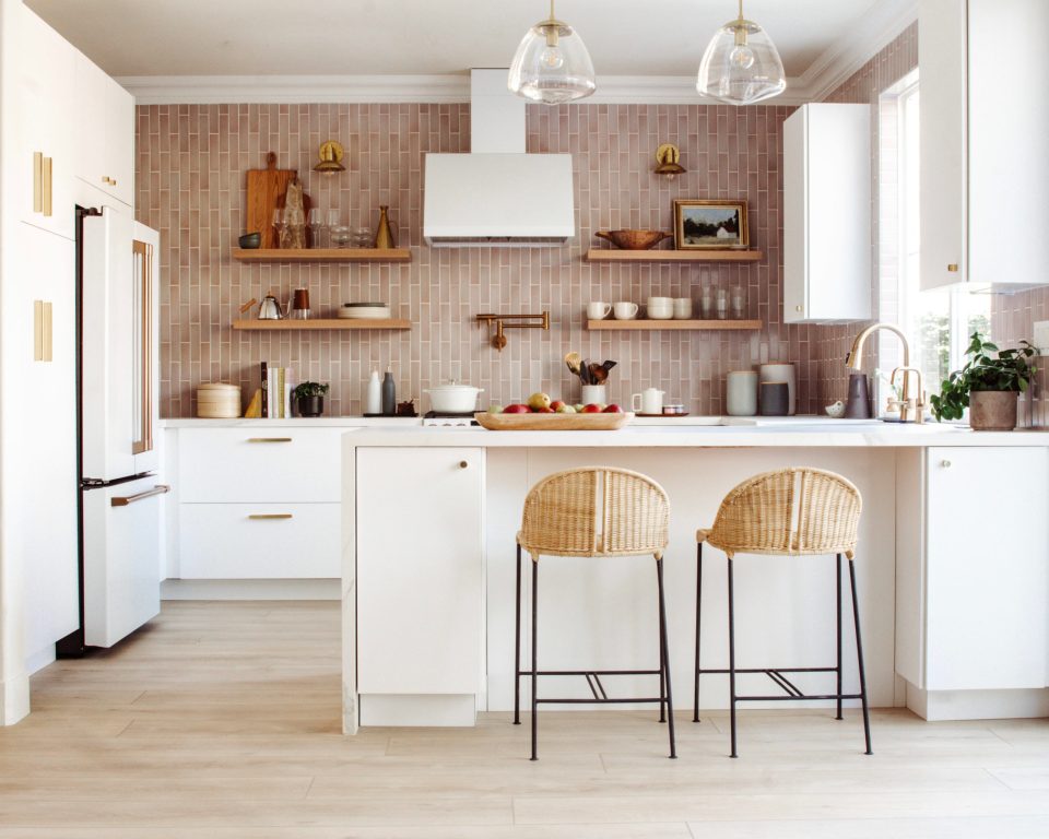 The full kitchen in view, with two pendant lighting over the peninsula and small sconces illuminating open shelving