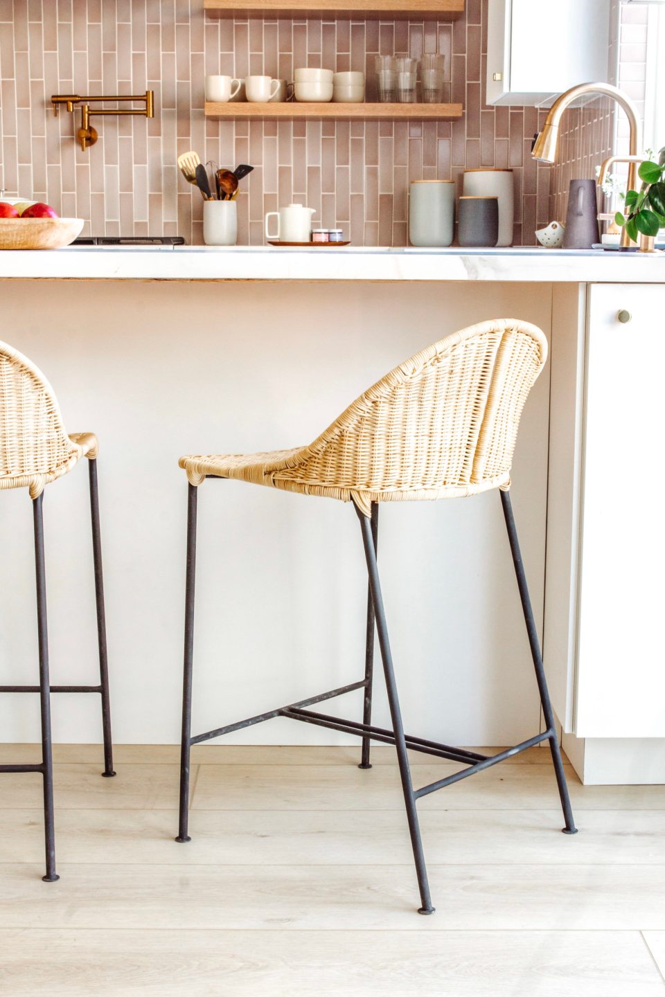 A rattan stool with matte black wire legs pulled up to the new peninsula 