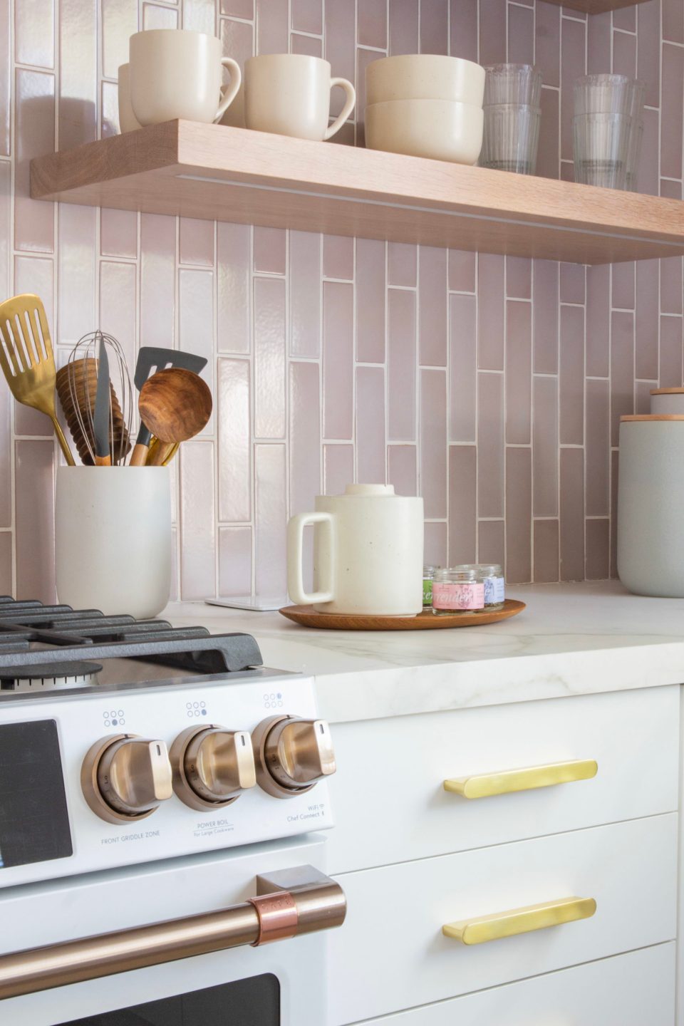 A close up on the cabinet's brass hardware beside the range's coppery handles